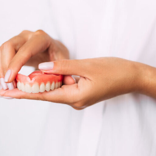 The dentist is holding dentures in his hands. Dental prosthesis in the hands of the doctor close-up. Dentistry conceptual photo. Prosthetic dentistry. False teeth. Removable denture