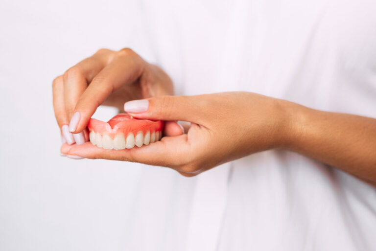 The dentist is holding dentures in his hands. Dental prosthesis in the hands of the doctor close-up. Dentistry conceptual photo. Prosthetic dentistry. False teeth. Removable denture